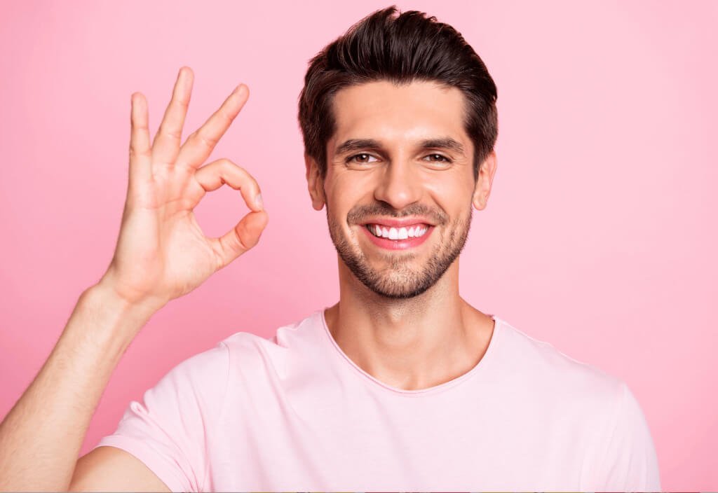 A man smiling and making an OK gesture