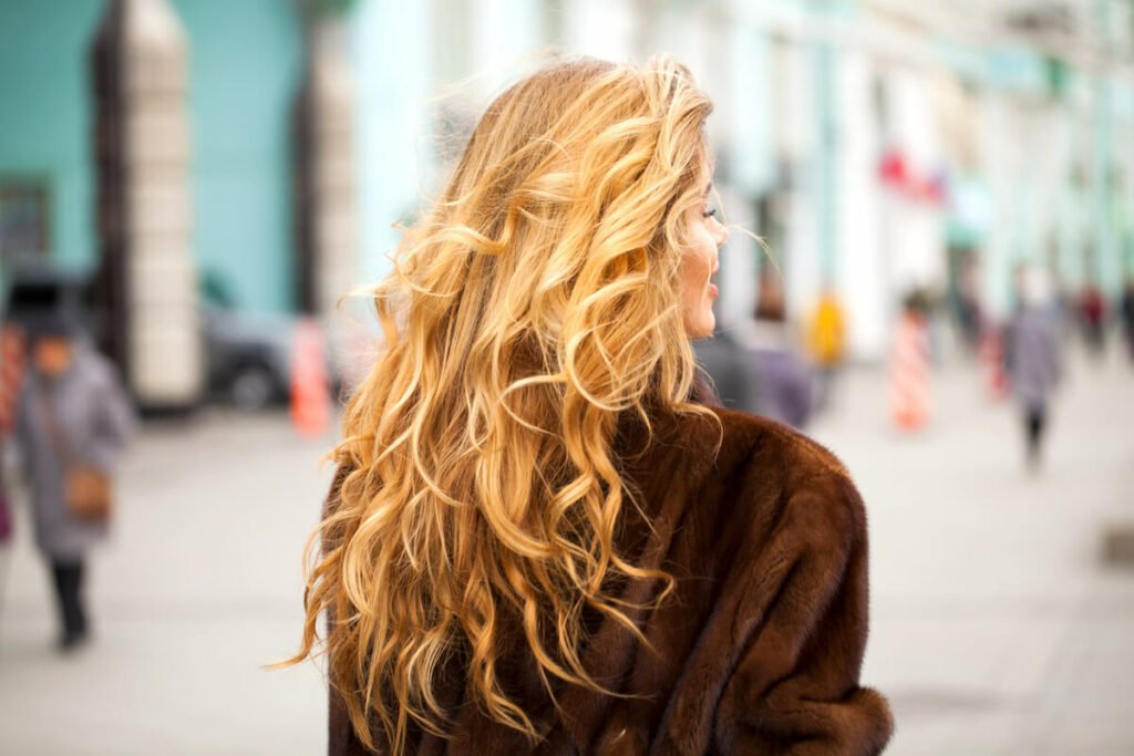 back of woman’s head with long, healthy brown hair with blonde highlights