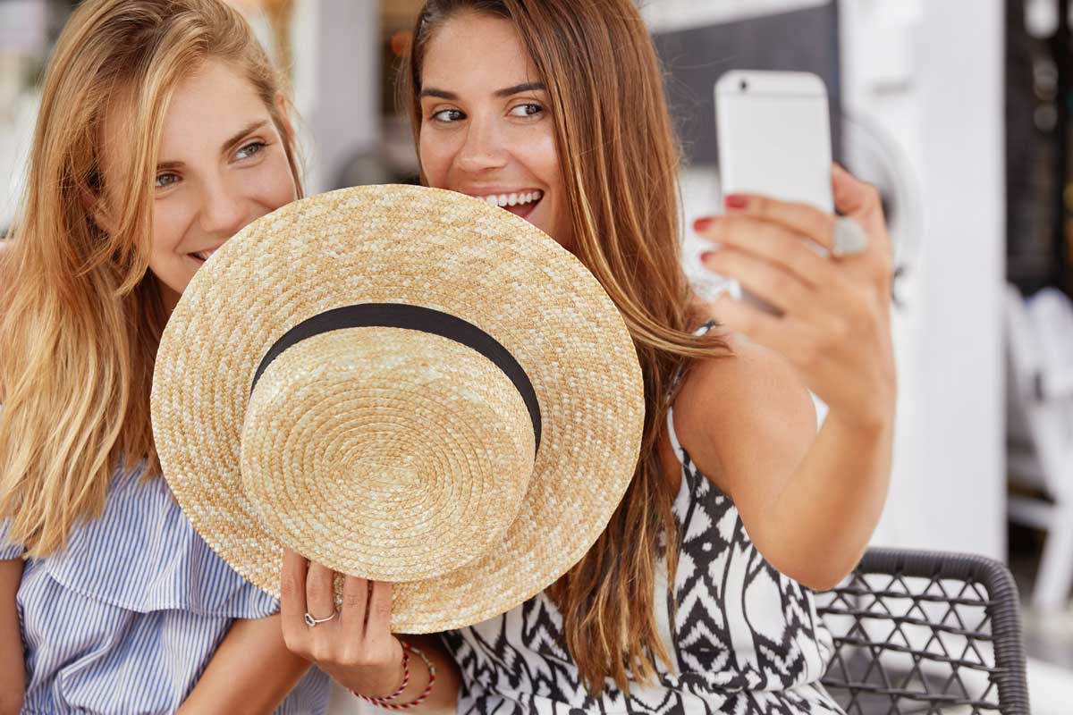 two women hiding behind hat