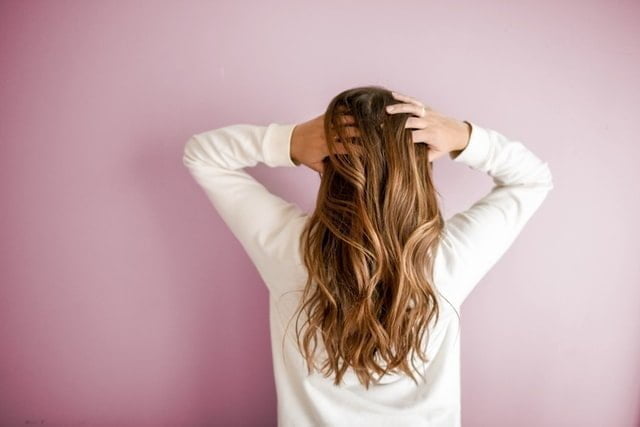 woman gently brushing long hair with hands