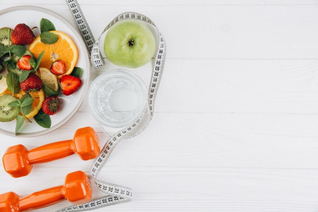 Healthy fruits on a table with barbells and a tape measure