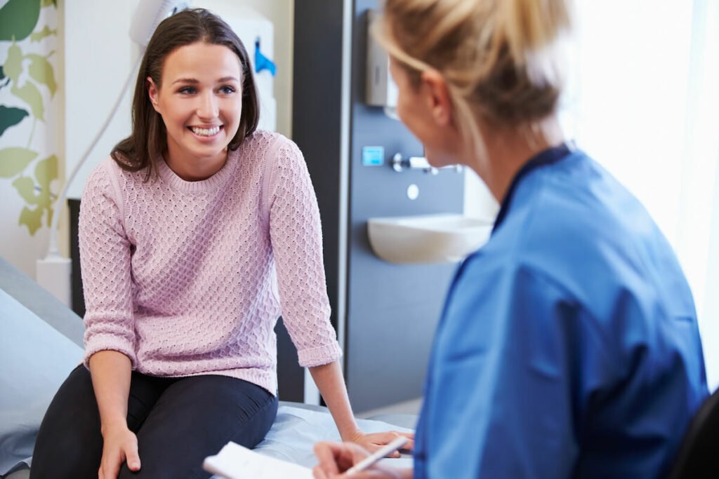 A smiling woman consults with a medical professional in a clinical setting
