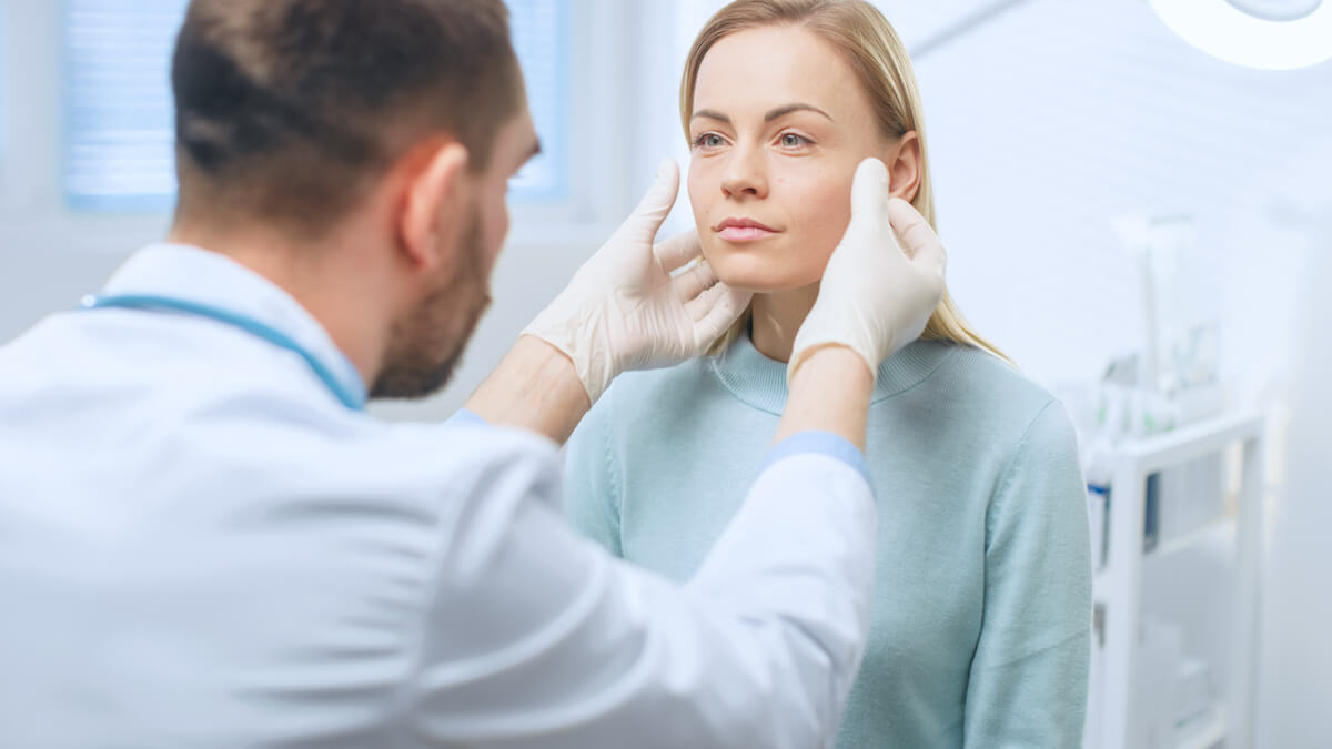 A woman receives a consultation from a plastic surgeon in a clinical setting