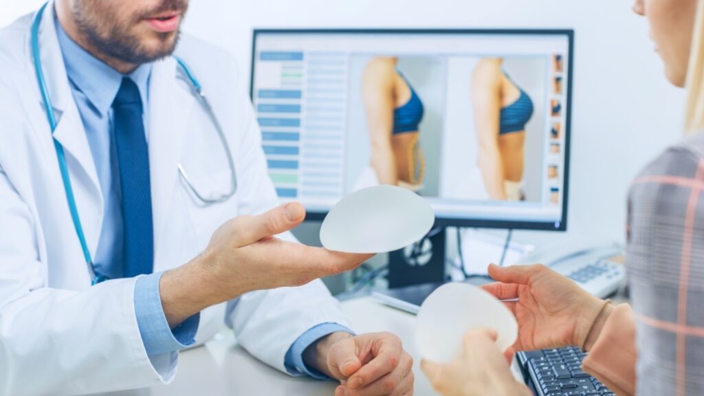 Doctor holding and explaining the breast implants to the patient.