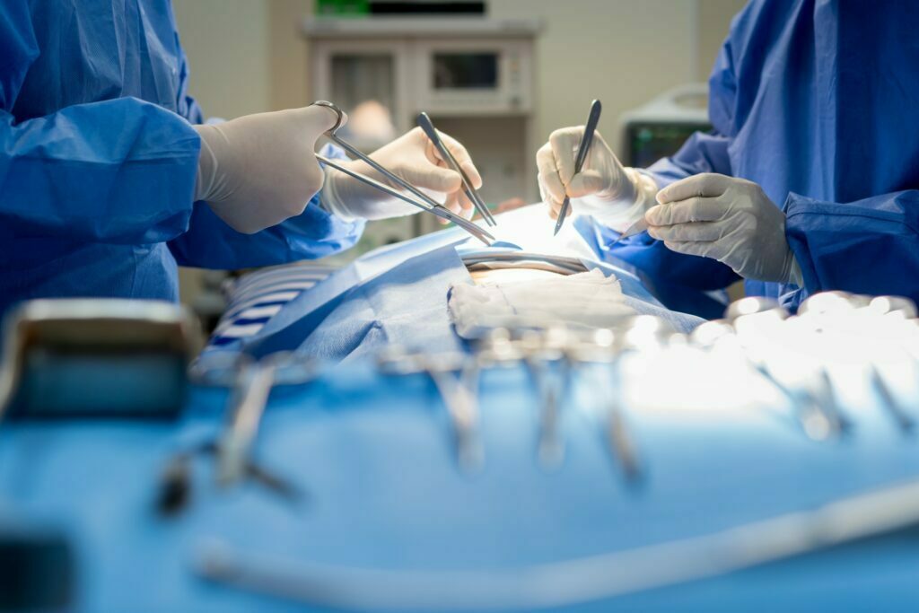 two doctors doing  tummy tuck operation stitches to the patient