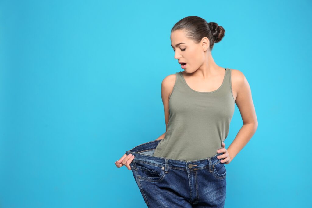 Slim woman in oversized jeans on color background, space for text. Weight loss