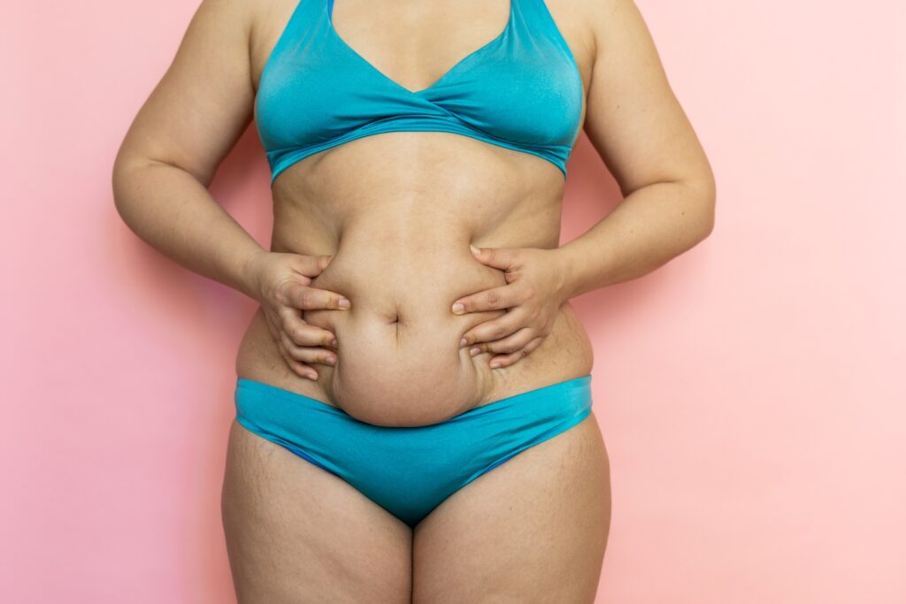 Woman in Underwear Touching Her Belly on White Background, Closeup