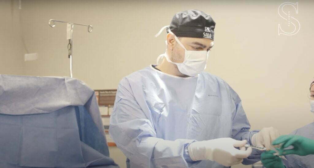 Dr. Saba wearing scrub suit preparing a tumescent solution for a liposuction for men patient in Indiana.